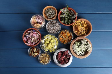Many different herbs in bowls on blue wooden table, flat lay
