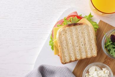 Photo of Tasty sandwich with ham served on white wooden table, flat lay. Space for text