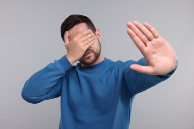 Photo of Embarrassed man covering face on light grey background