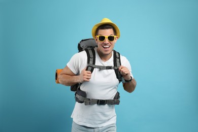 Male tourist with travel backpack on turquoise background