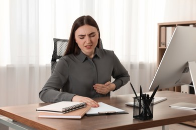 Photo of Woman having heart attack at table in office