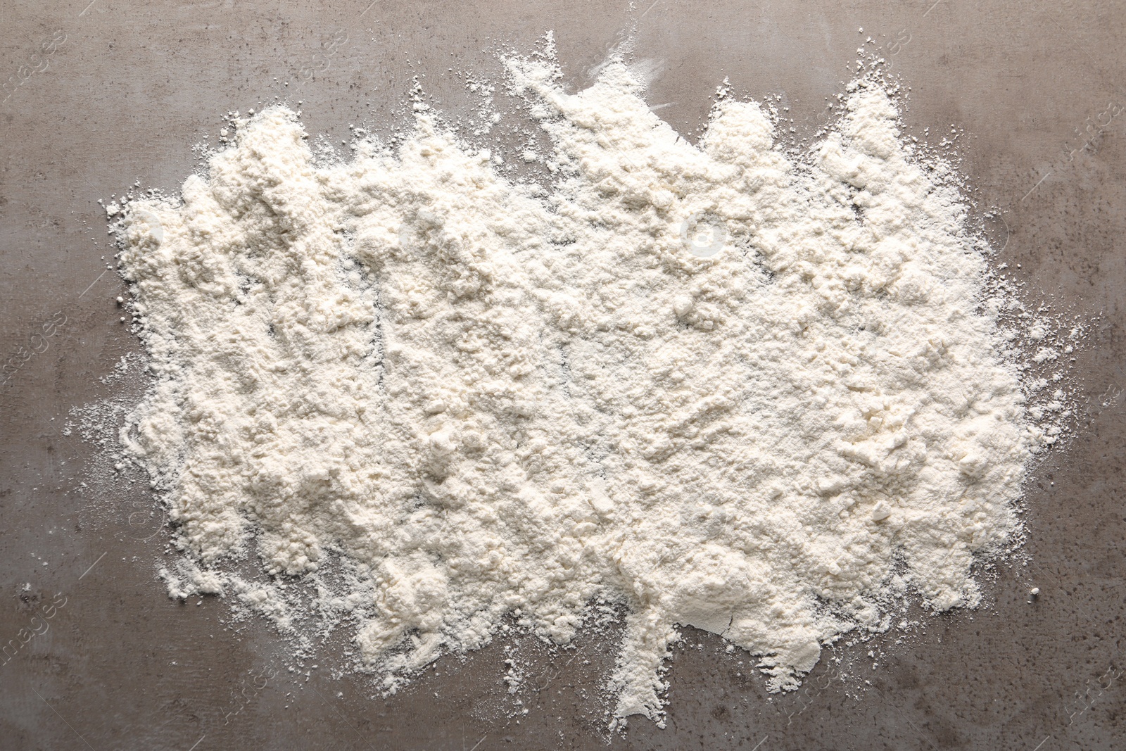 Photo of Scattered flour on grey textured table, top view