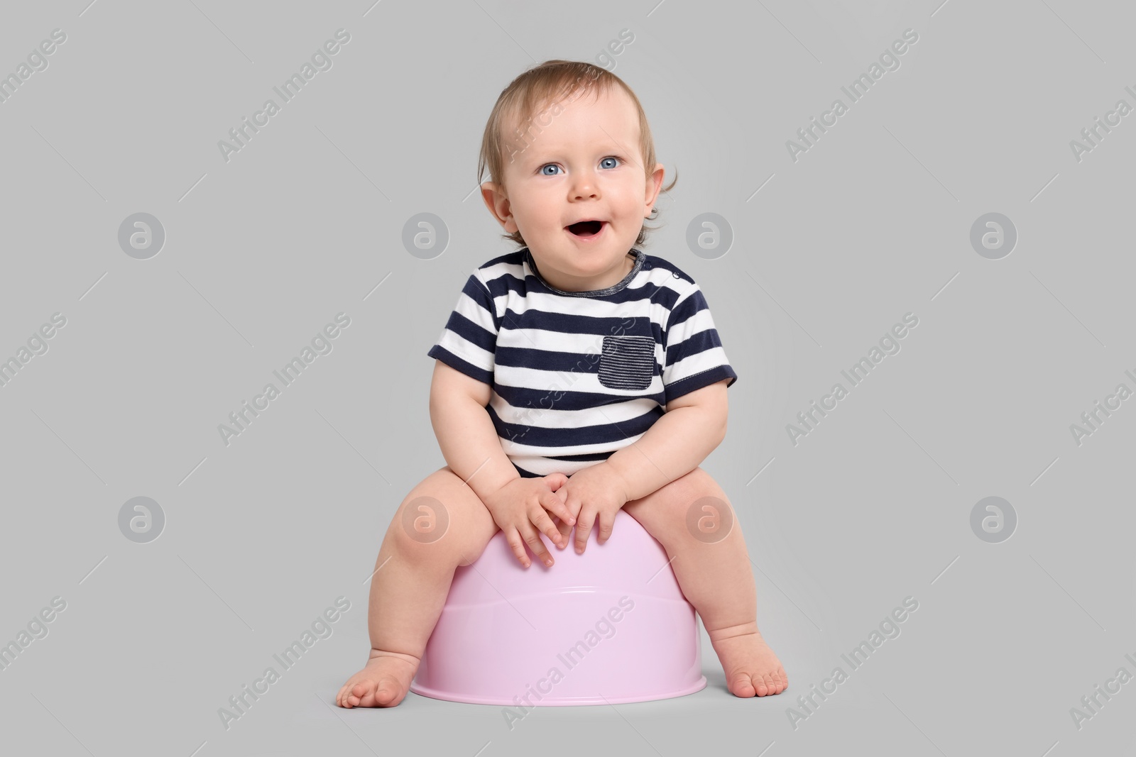 Photo of Little child sitting on baby potty against light grey background