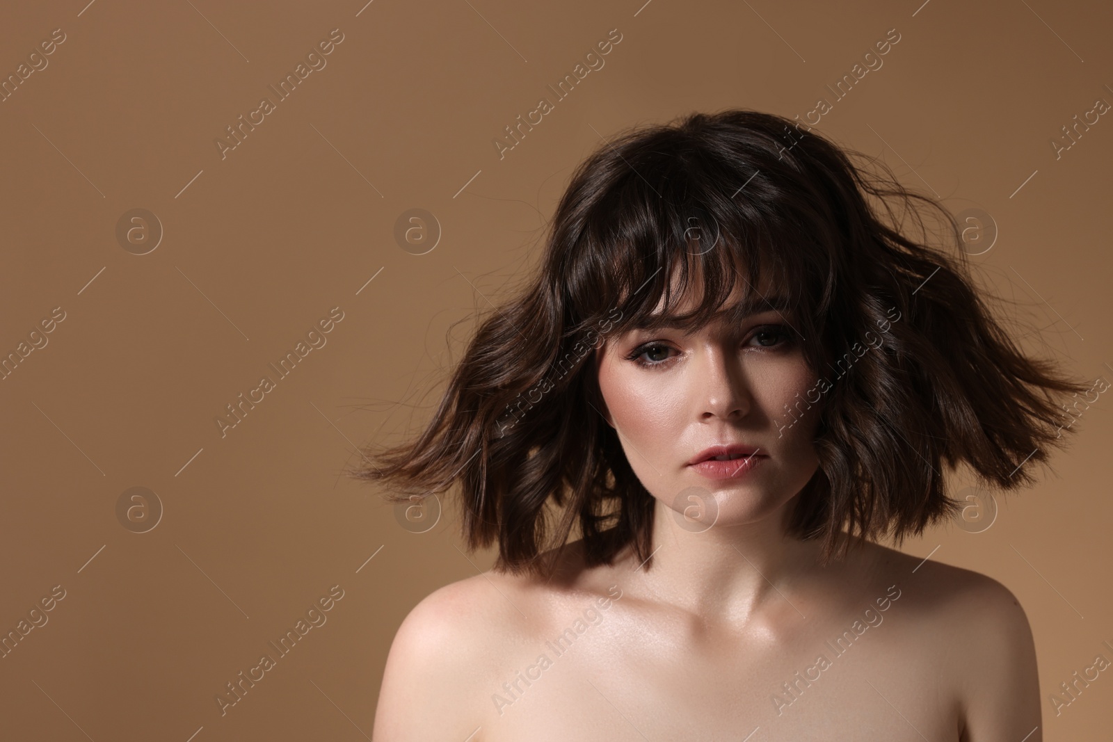Photo of Portrait of beautiful young woman with wavy hairstyle on brown background. Space for text