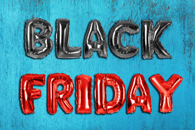 Phrase BLACK FRIDAY made of foil balloon letters on blue wooden background