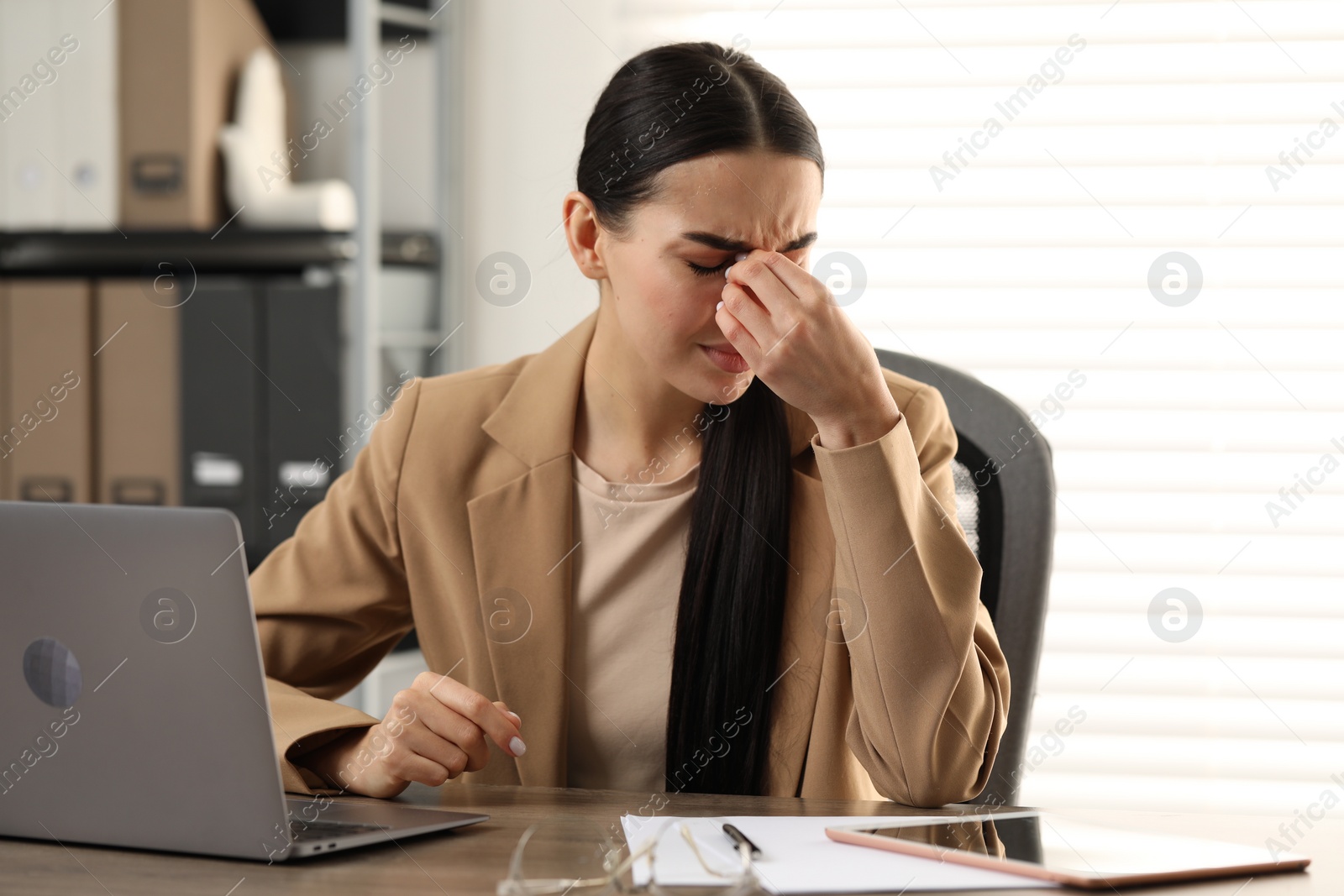 Photo of Woman suffering from headache at workplace in office