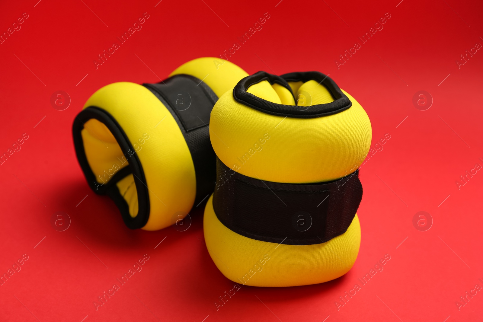 Photo of Stylish yellow weighting agents on red background