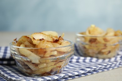 Tasty fried onion in glass bowl on table, closeup