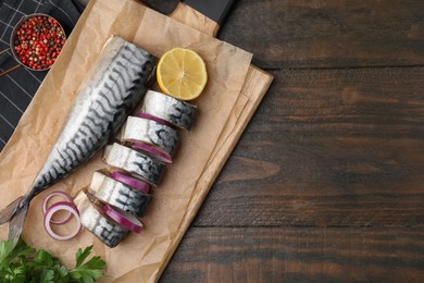 Photo of Tasty salted mackerel, onion and lemon on wooden table, flat lay. Space for text