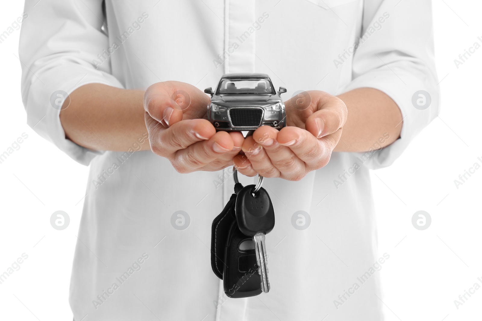 Photo of Woman holding key and miniature automobile model on white background, closeup. Car buying