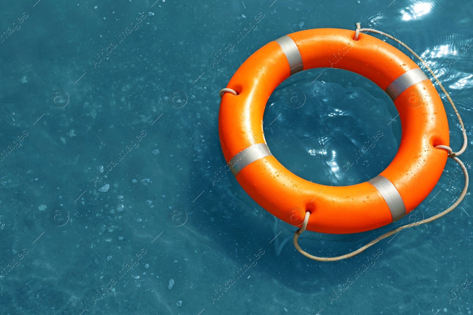 Photo of Orange life buoy floating in sea, above view. Emergency rescue equipment