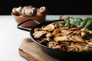 Photo of Delicious cooked mushrooms in frying pan on table