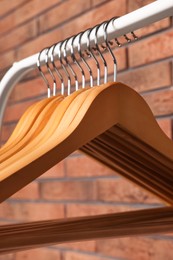 Photo of Wooden clothes hangers on rack near red brick wall, closeup