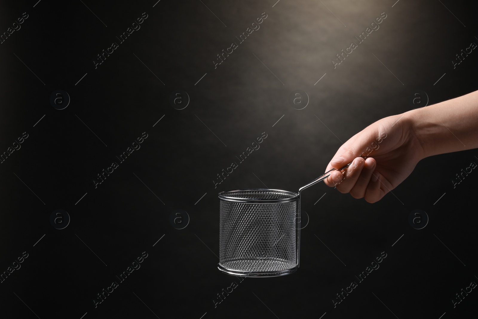 Photo of Woman holding metal basket for French fries on black background, closeup. Space for text