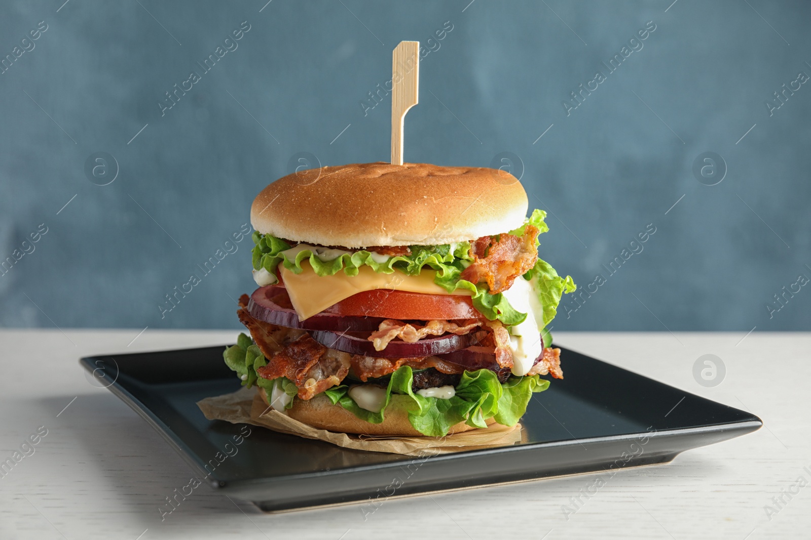 Photo of Tasty burger with bacon served on table