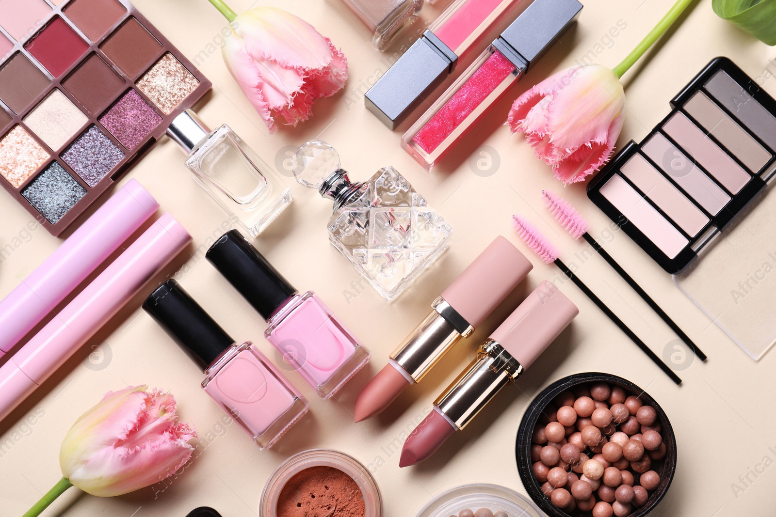 Photo of Flat lay composition with different makeup products and beautiful spring flowers on beige background