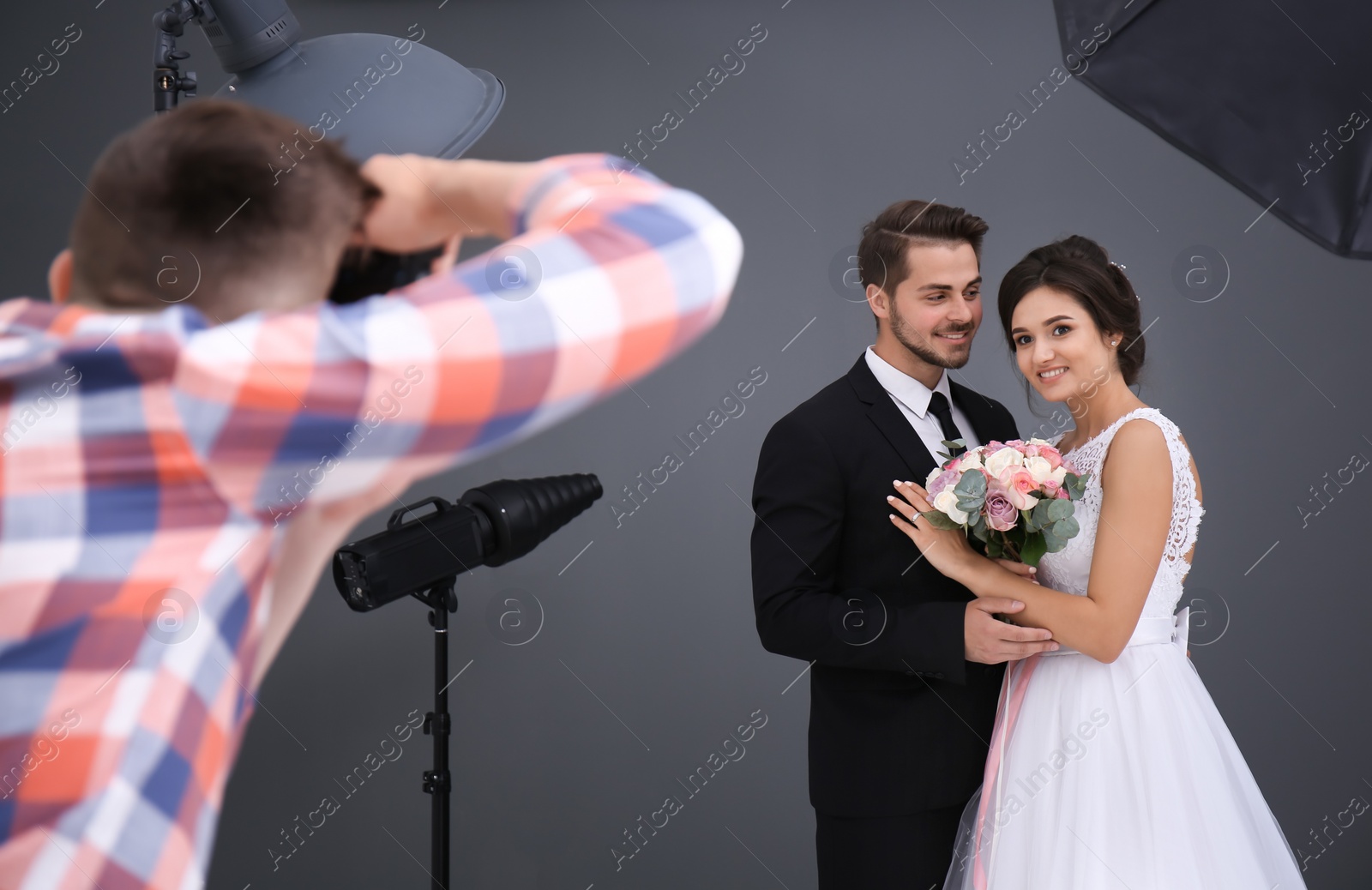 Photo of Professional photographer taking photo of wedding couple in studio