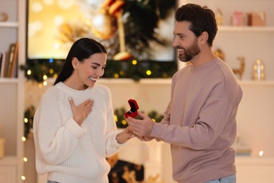 Photo of Making proposal. Man with engagement ring surprising his girlfriend at home on Christmas