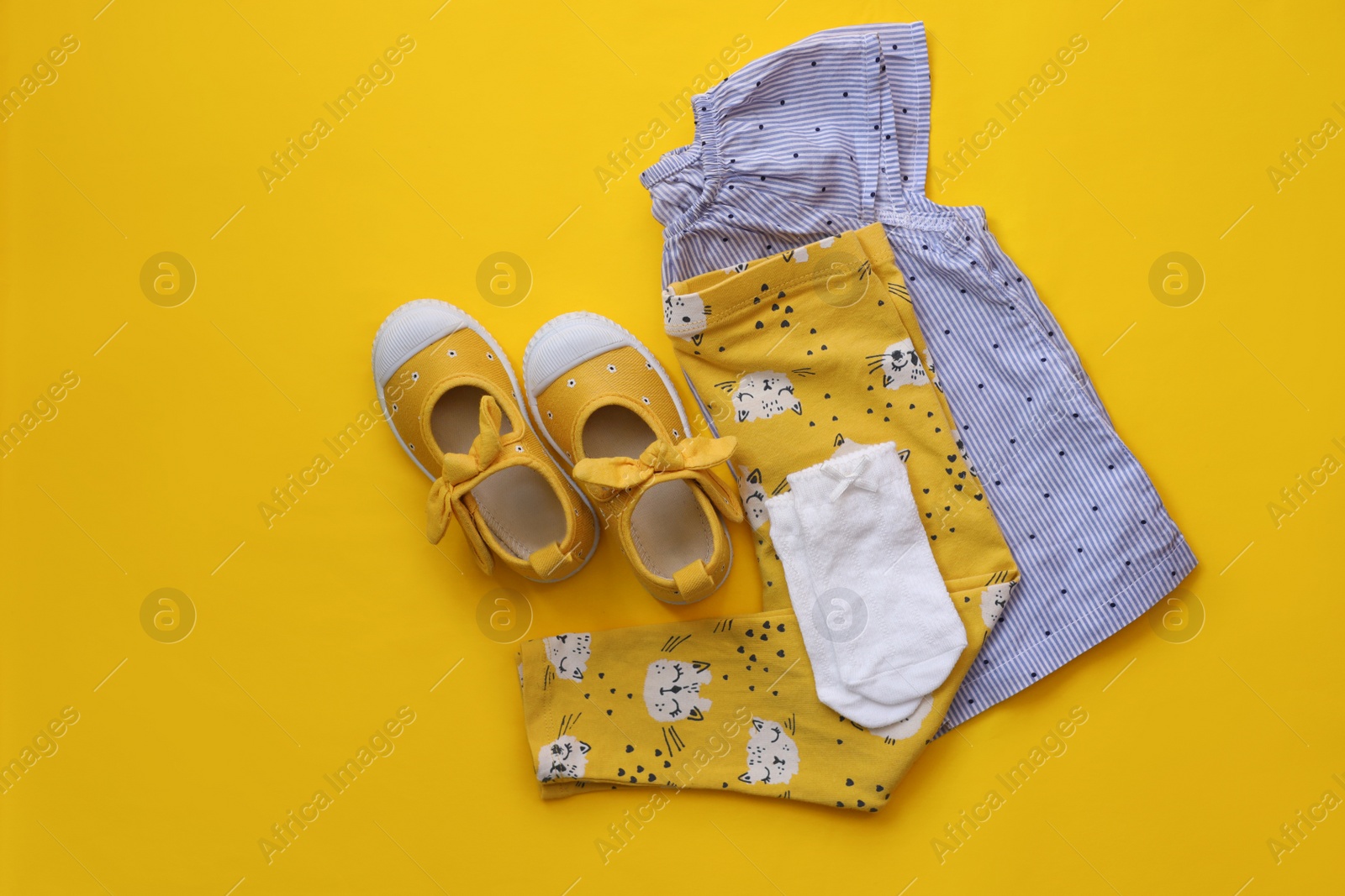 Photo of Stylish child clothes and shoes on yellow background, flat lay