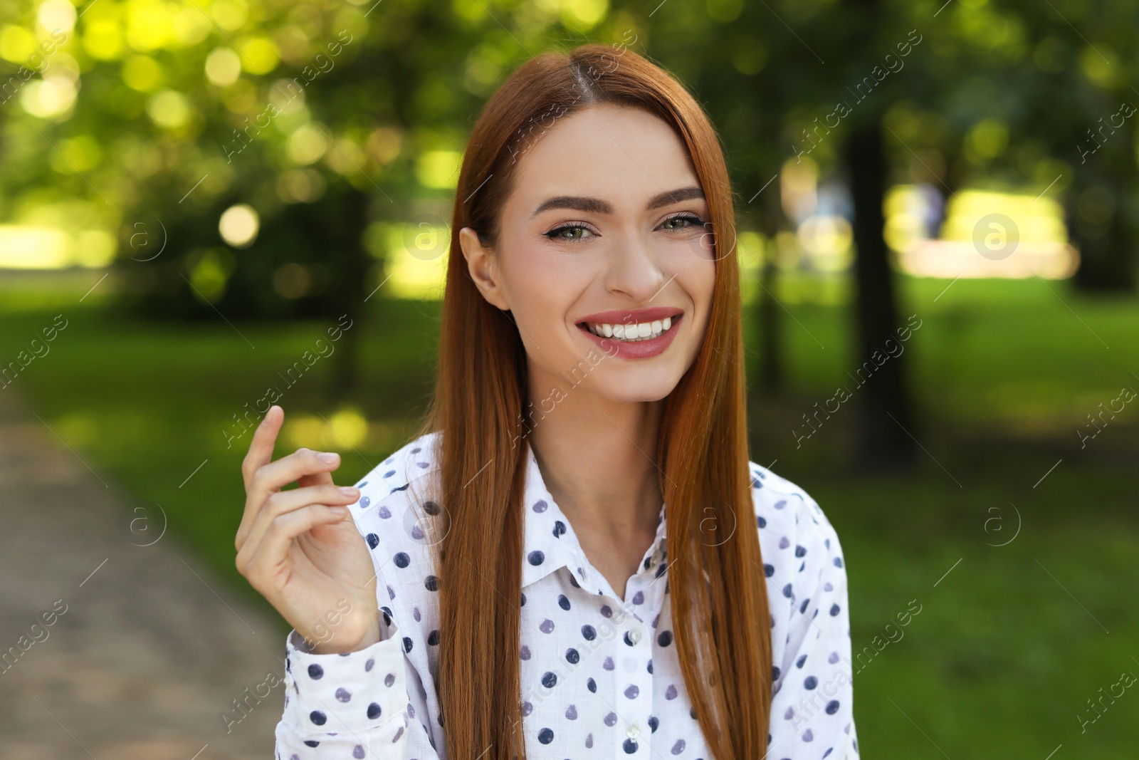 Photo of Portrait of charming young woman with beautiful smile in park. Attractive lady posing for camera