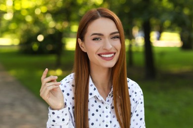 Portrait of charming young woman with beautiful smile in park. Attractive lady posing for camera