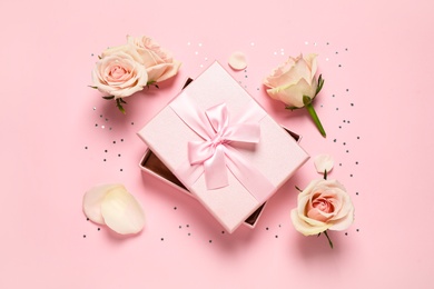 Photo of Elegant gift box, beautiful flowers and confetti on pink background, flat lay