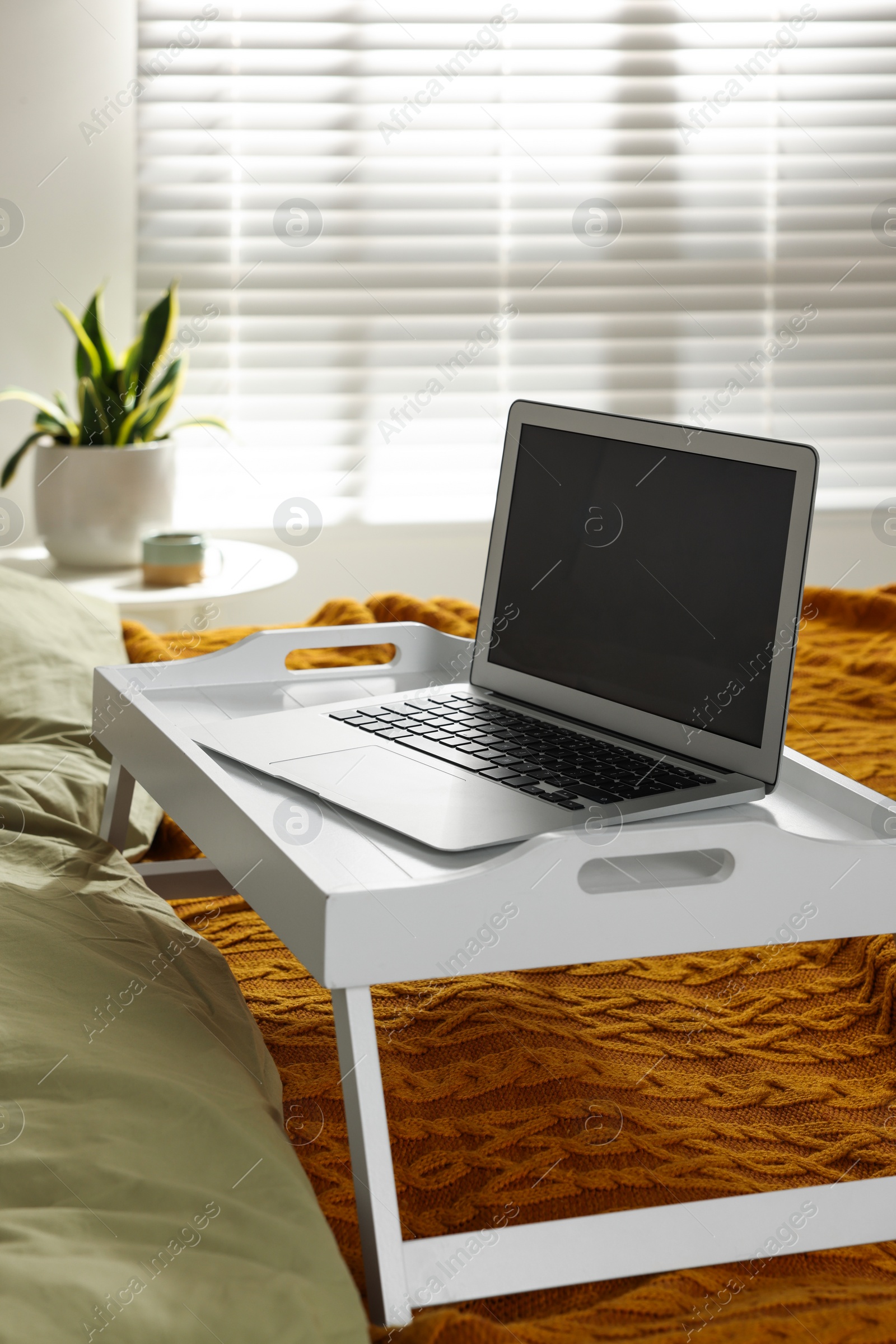 Photo of White tray with modern laptop on bed indoors