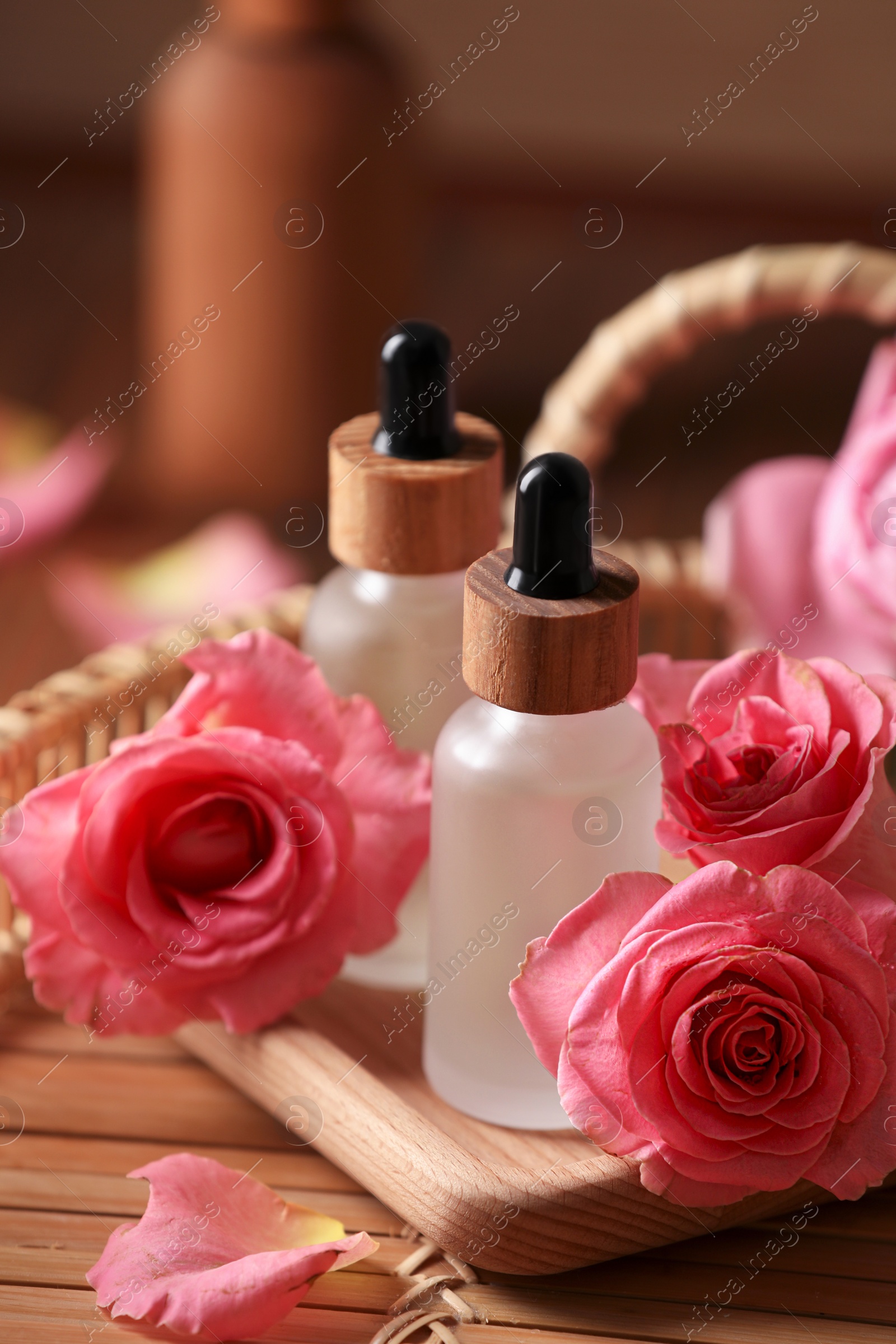 Photo of Bottles of essential rose oil and flowers on tray