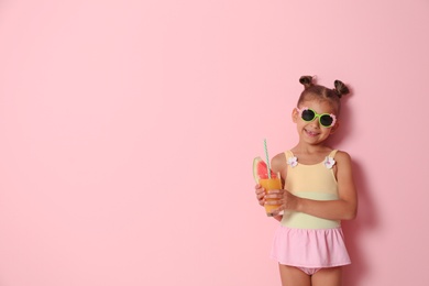 Cute little girl with glass of cocktail on color background