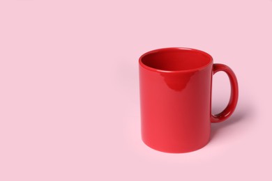 Photo of Red ceramic mug on pink background, space for text