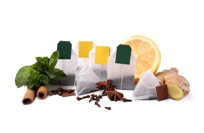 Photo of Different tea bags, spices and half of lemon on white background