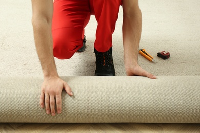 Worker rolling out new carpet flooring indoors, closeup