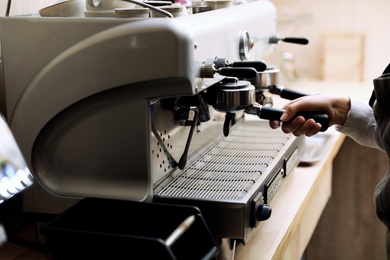 Photo of Barista preparing coffee using modern machine, closeup