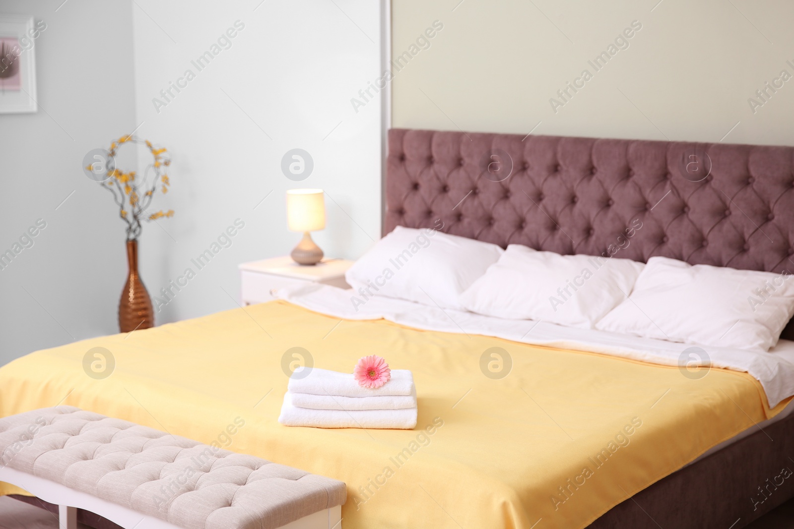 Photo of Luxury bed with stack of towels and flower in hotel room