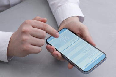 Image of Electronic signature. Man using mobile phone at grey table, closeup