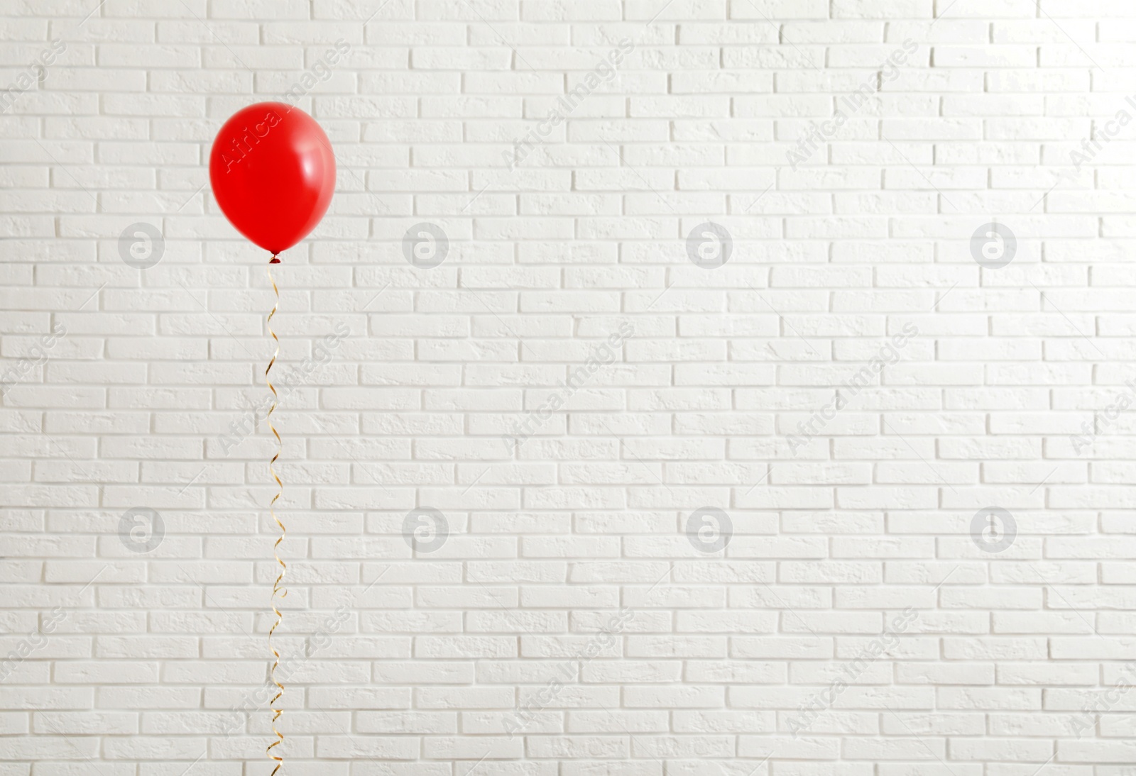 Photo of Bright balloon near brick wall, space for text. Celebration time