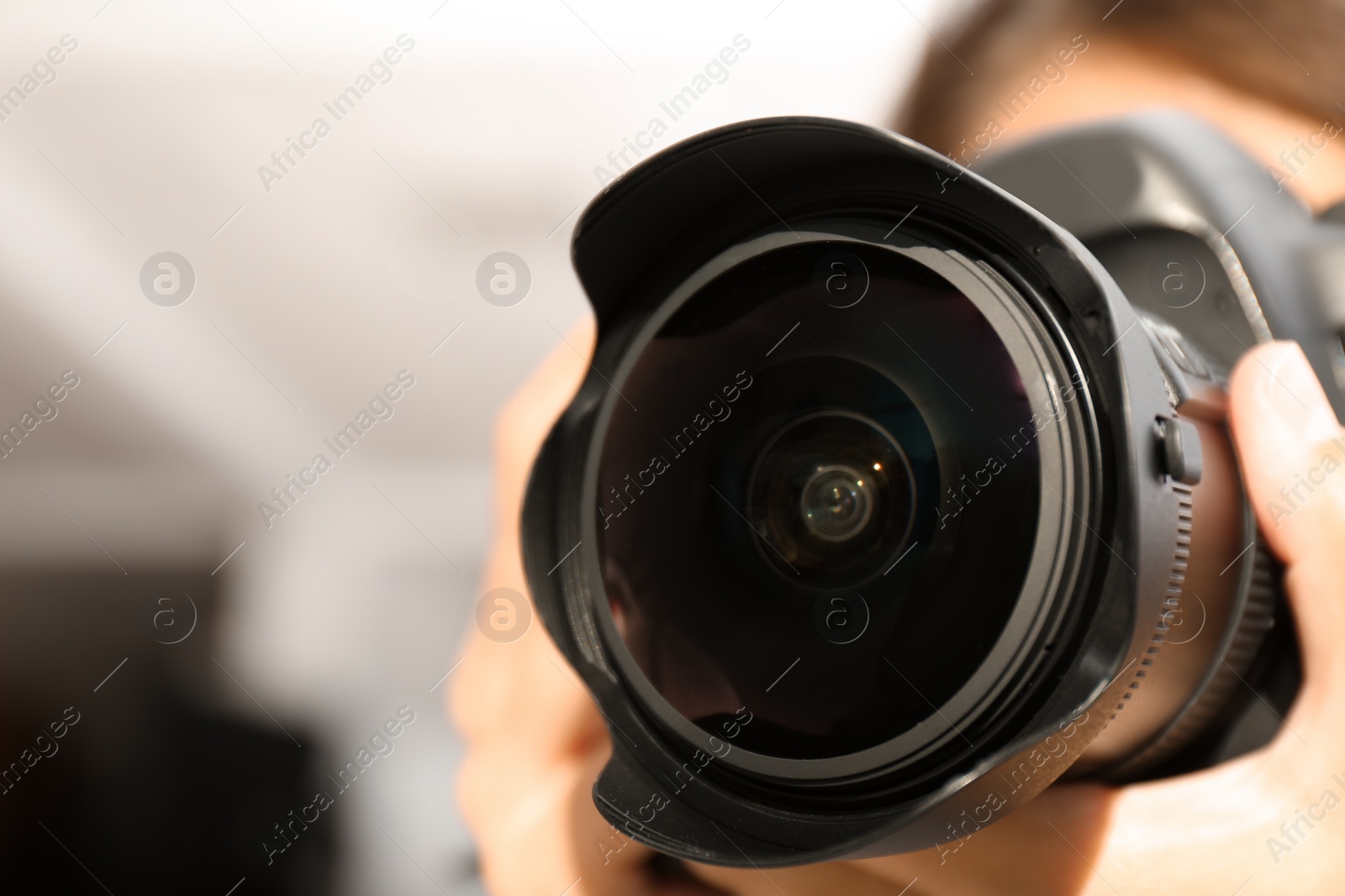 Photo of Female photographer with professional camera on blurred background, closeup