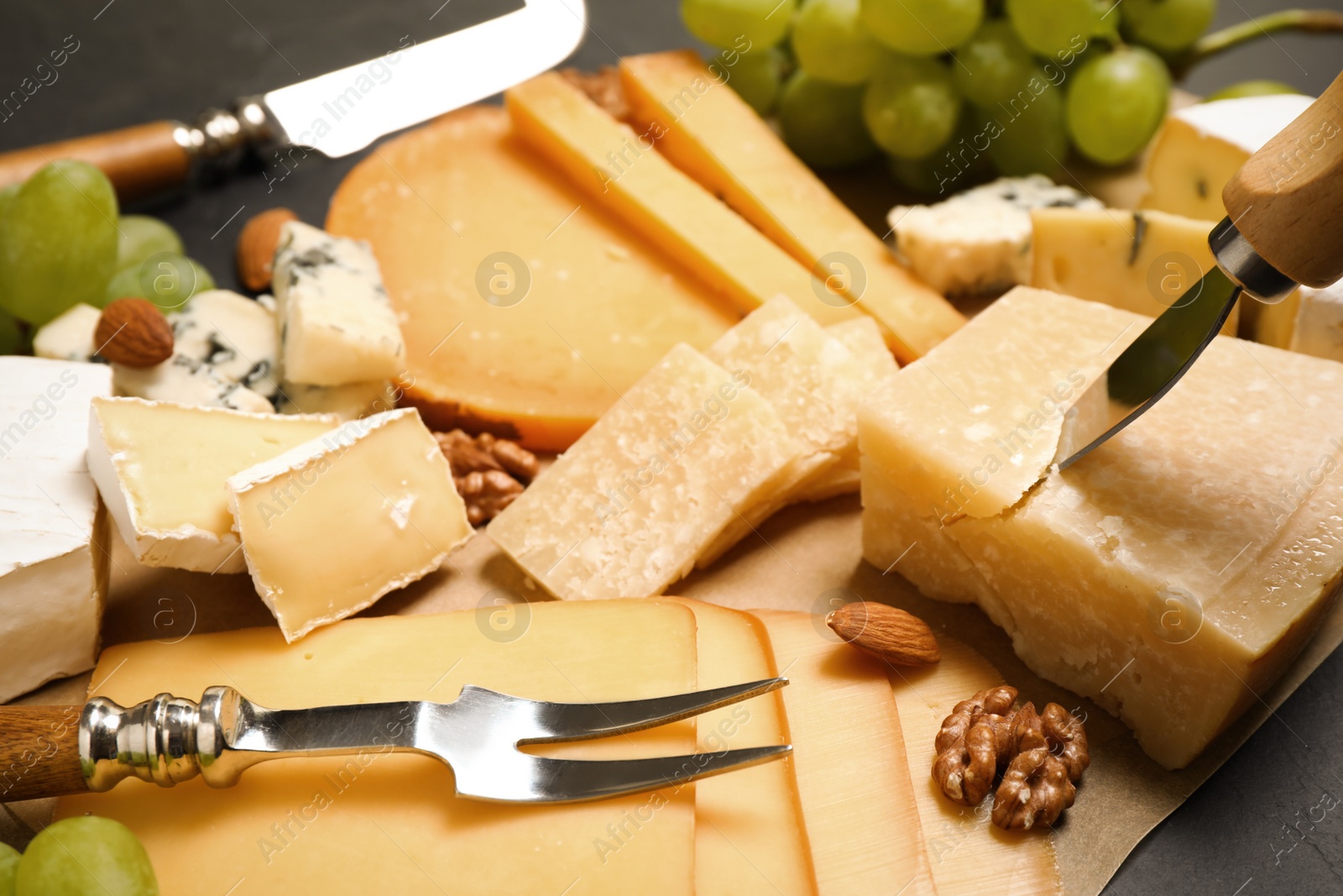 Photo of Composition with different sorts of cheese and knives on parchment, closeup