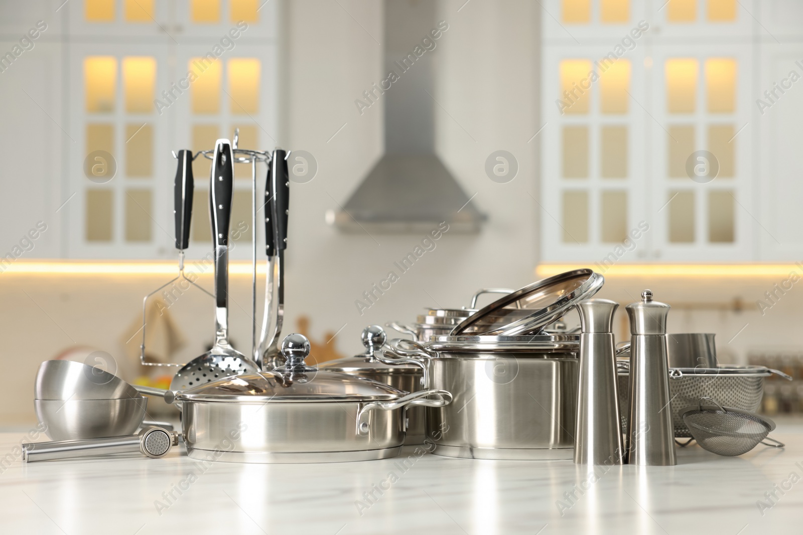 Photo of Set of shiny cooking utensils on table in kitchen