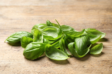 Photo of Fresh green basil leaves on wooden table