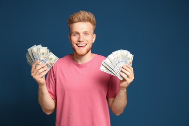 Photo of Portrait of happy lottery winner with money on blue background