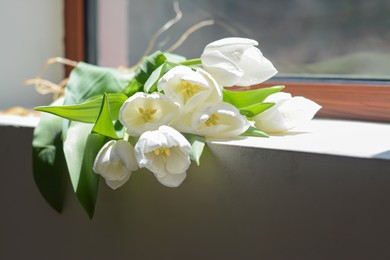 Photo of Bouquet of beautiful white tulip flowers on windowsill indoors, closeup