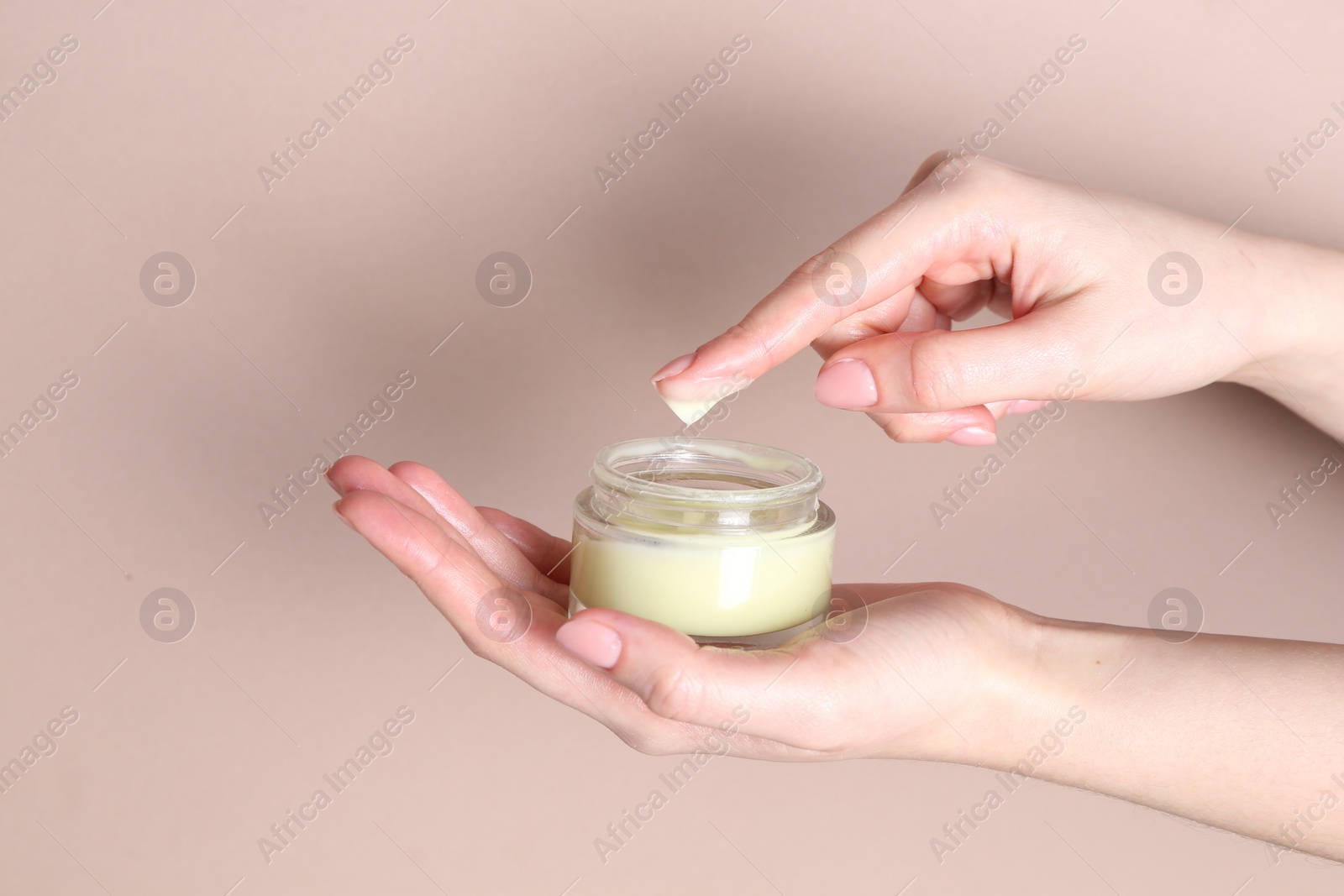 Photo of Woman with jar of cream on beige background, closeup