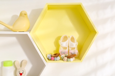 Photo of Hexagon shaped shelves with toys and child's accessories on white wall. Interior design