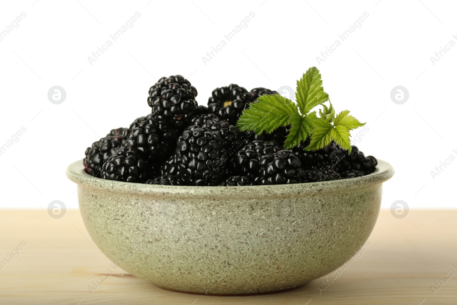 Photo of Bowl with fresh ripe blackberries on wooden table against white background