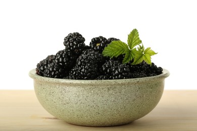 Photo of Bowl with fresh ripe blackberries on wooden table against white background