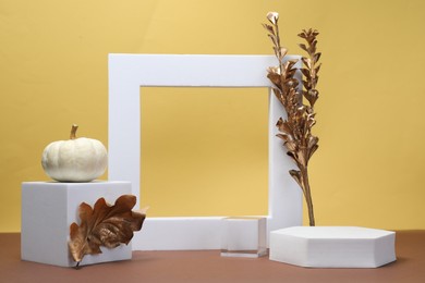 Photo of Autumn presentation for product. White geometric figures, pumpkin and golden branch on color background