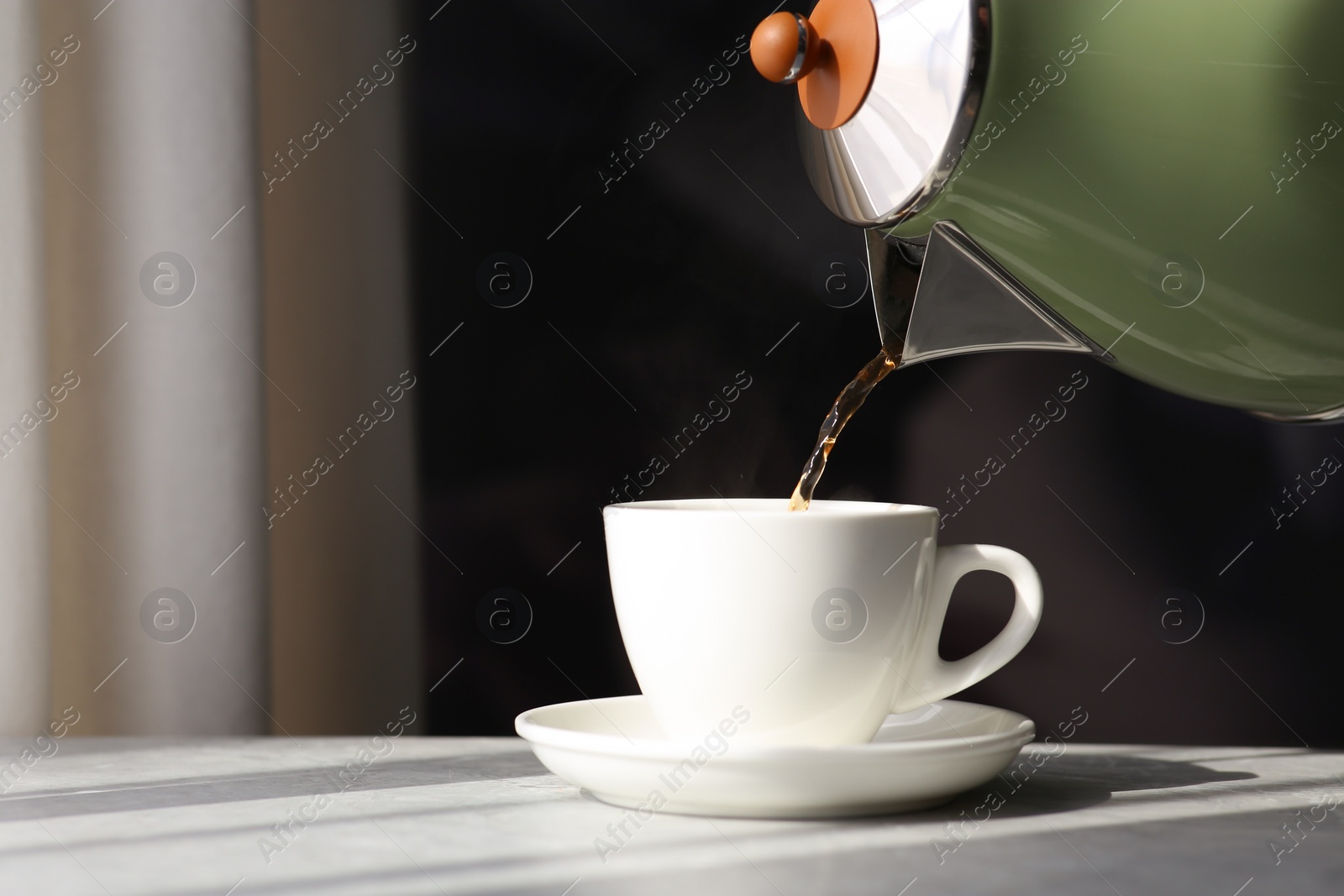 Photo of Pouring hot drink into cup on table. Good morning