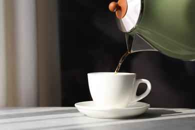 Photo of Pouring hot drink into cup on table. Good morning