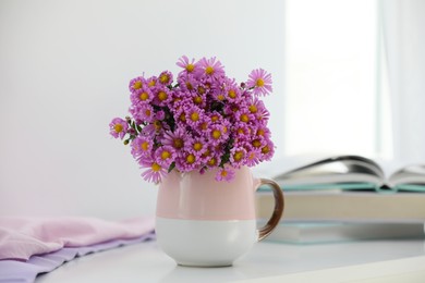 Photo of Cup with beautiful flowers on white table in light room